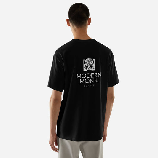 A person wearing a black Modern Monk t-shirt from the back, with text on the shirt that reads 'MODERN MONK'.