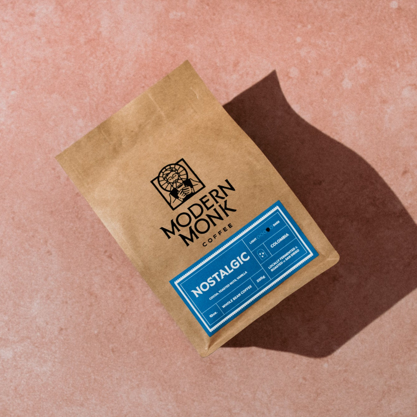 Kraft paper coffee bag with 'Modern Monk Coffee' branding on a pinkish-brown surface