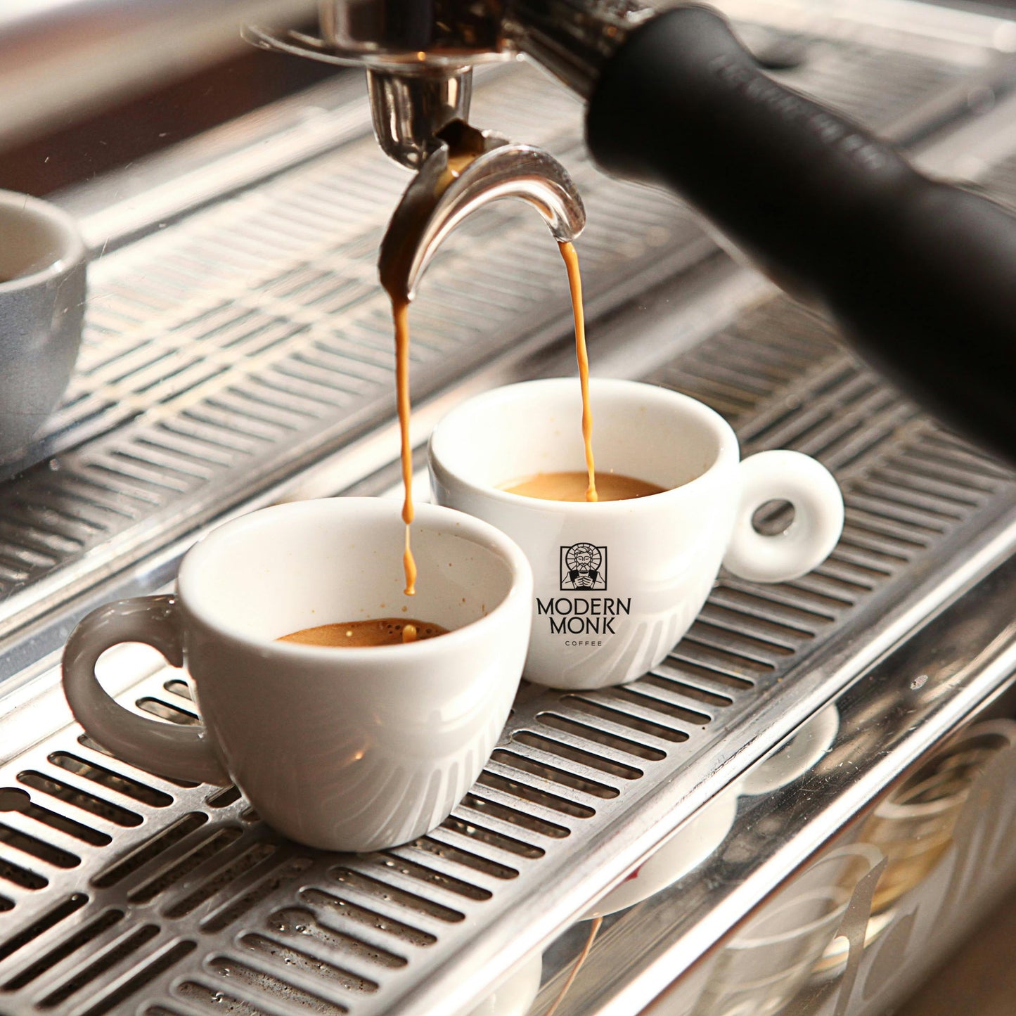 Espresso being poured into white cups on a modern espresso machine.