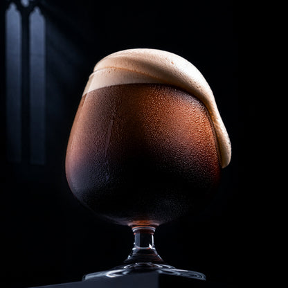 Glass of beer with a thick head on a black background