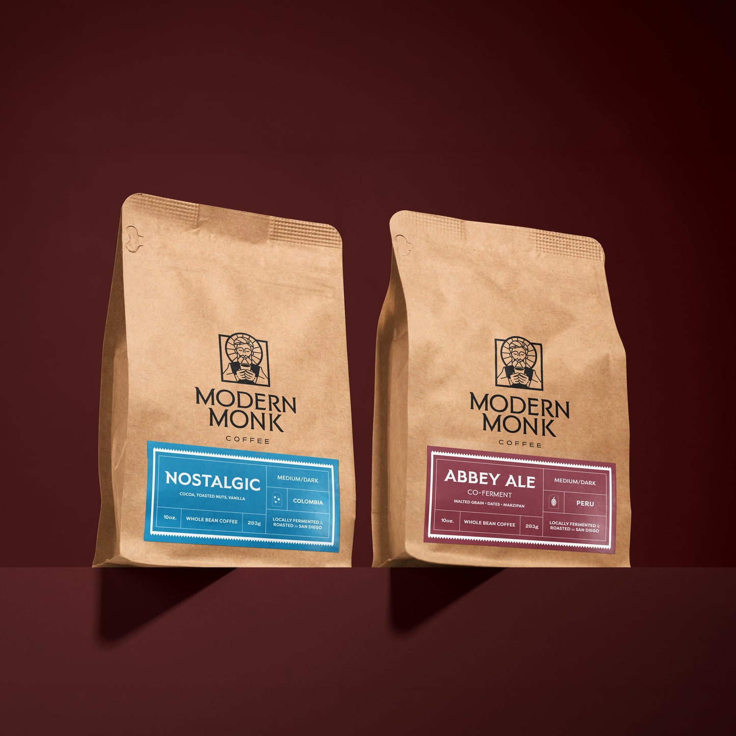 Two brown paper coffee bags with 'Modern Monk' branding on a dark red background