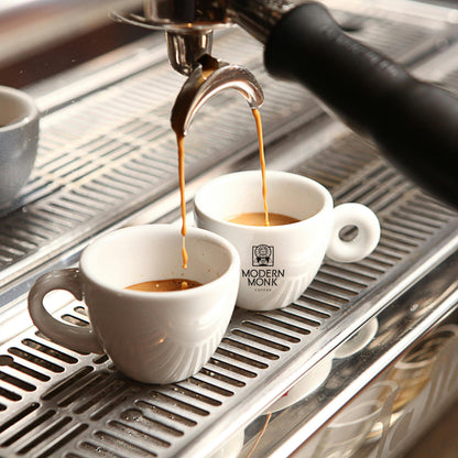 Espresso being poured into white cups on a modern espresso machine.