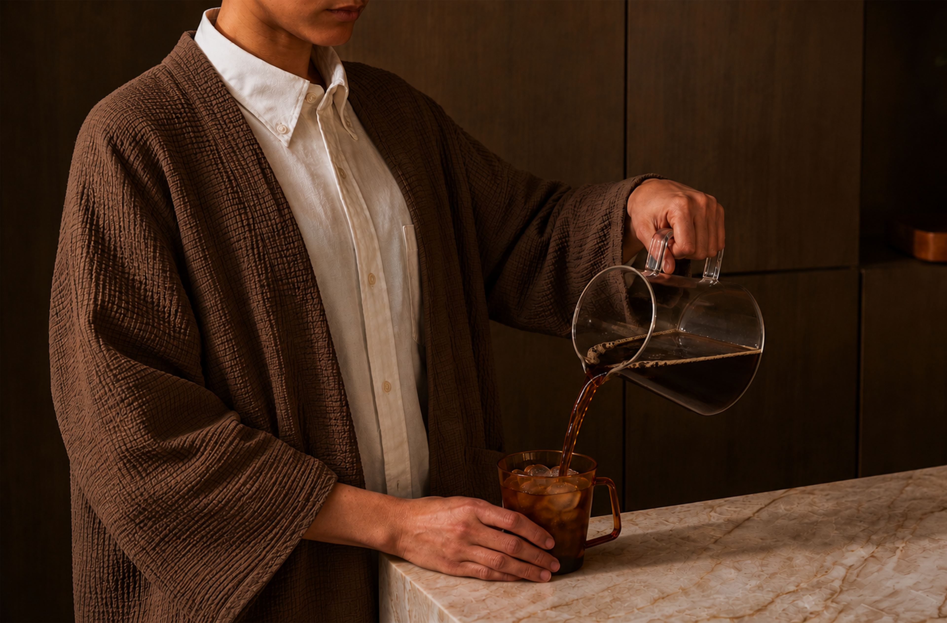 Person pouring coffee from a glass carafe into a mug on a marble surface.